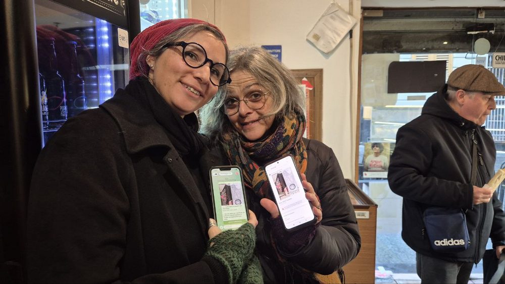 Two Ogigia customers holding garment tags outside the workshop in via di Pré
